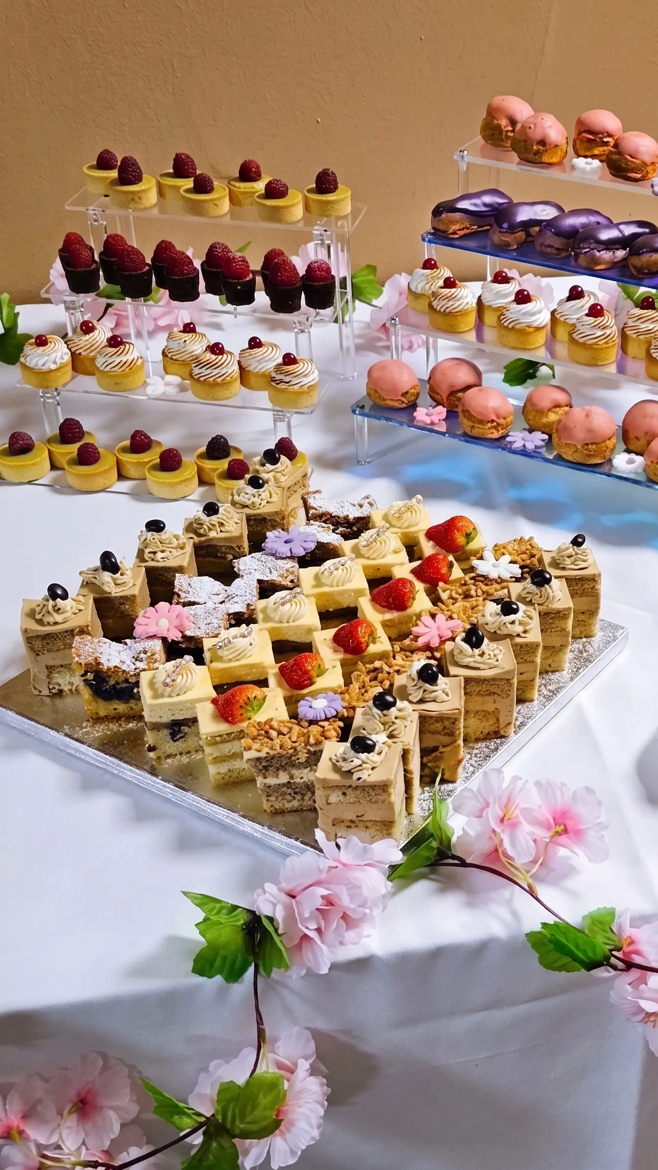 Dessert table with mini cakes, macarons, éclairs, fruit tartlets and assorted sweet pieces